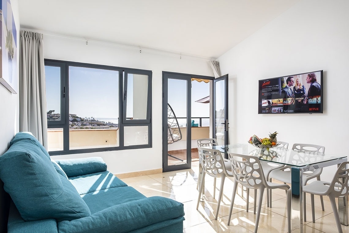 a living room with a blue couch and a netflix tv on the wall