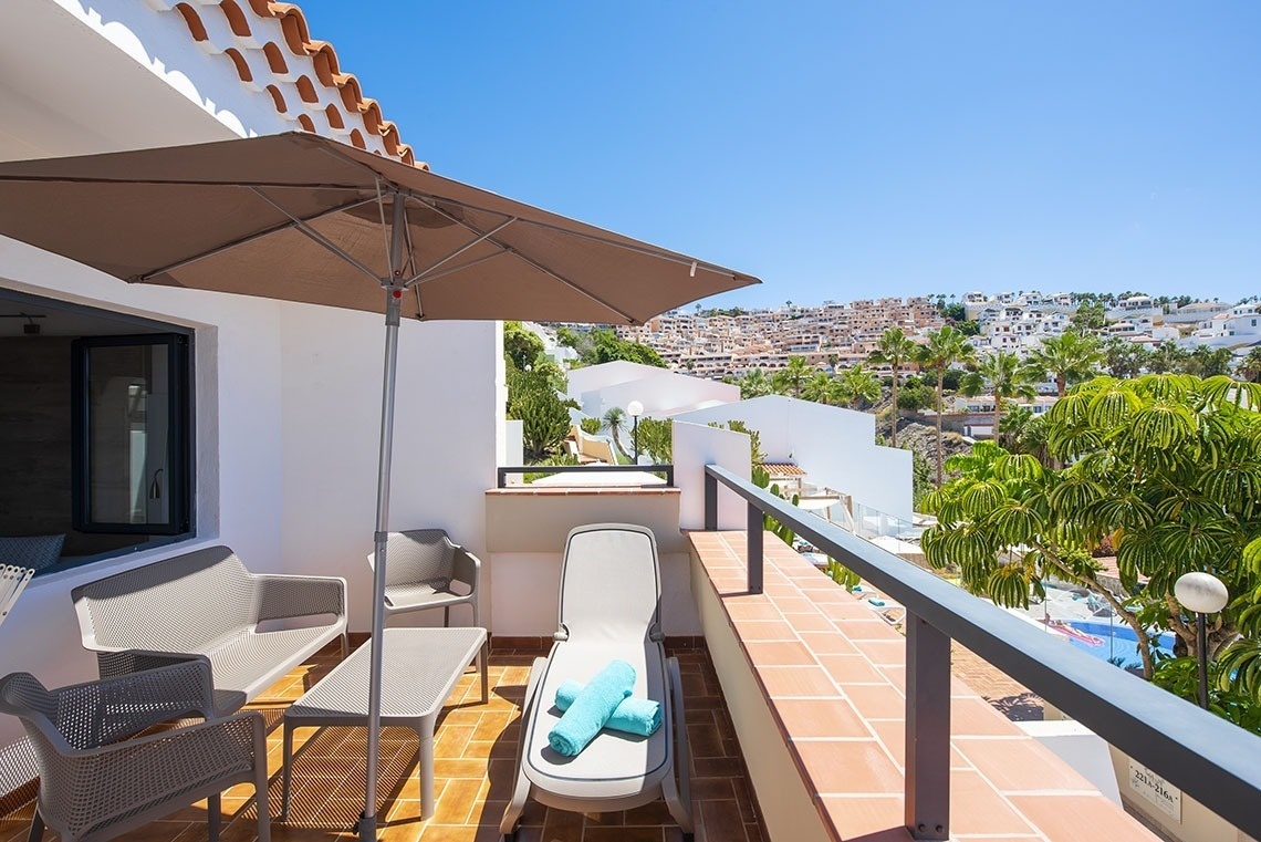 un balcon avec un parasol et une chaise longue