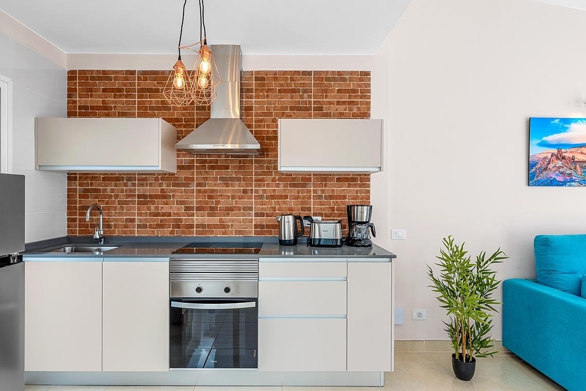 a kitchen with white cabinets and a brick wall