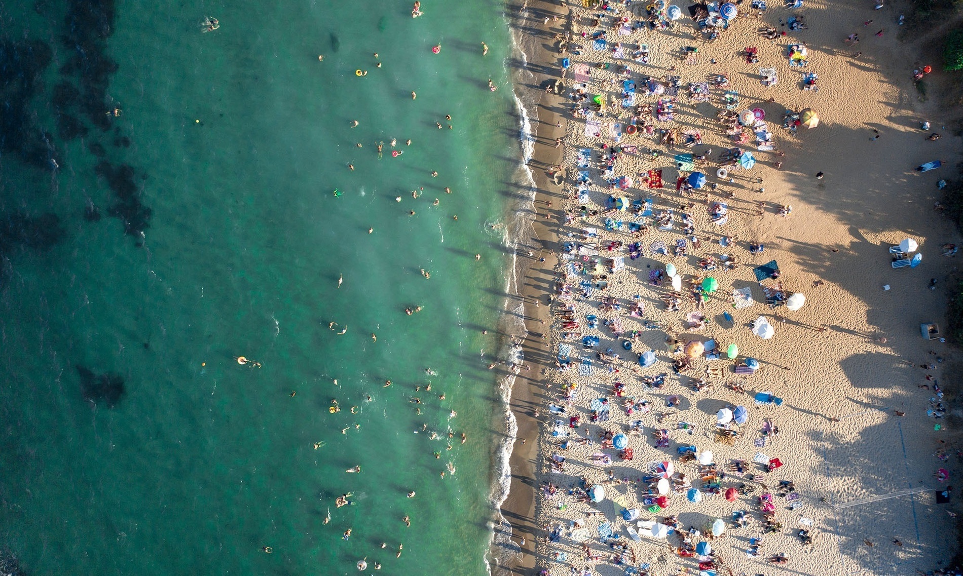 eine Luftaufnahme eines überfüllten Strandes an einem sonnigen Tag