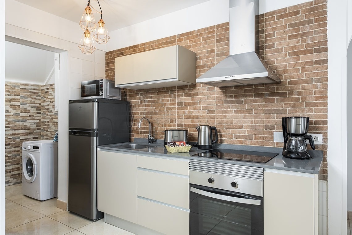a kitchen with a brick wall and a stainless steel refrigerator