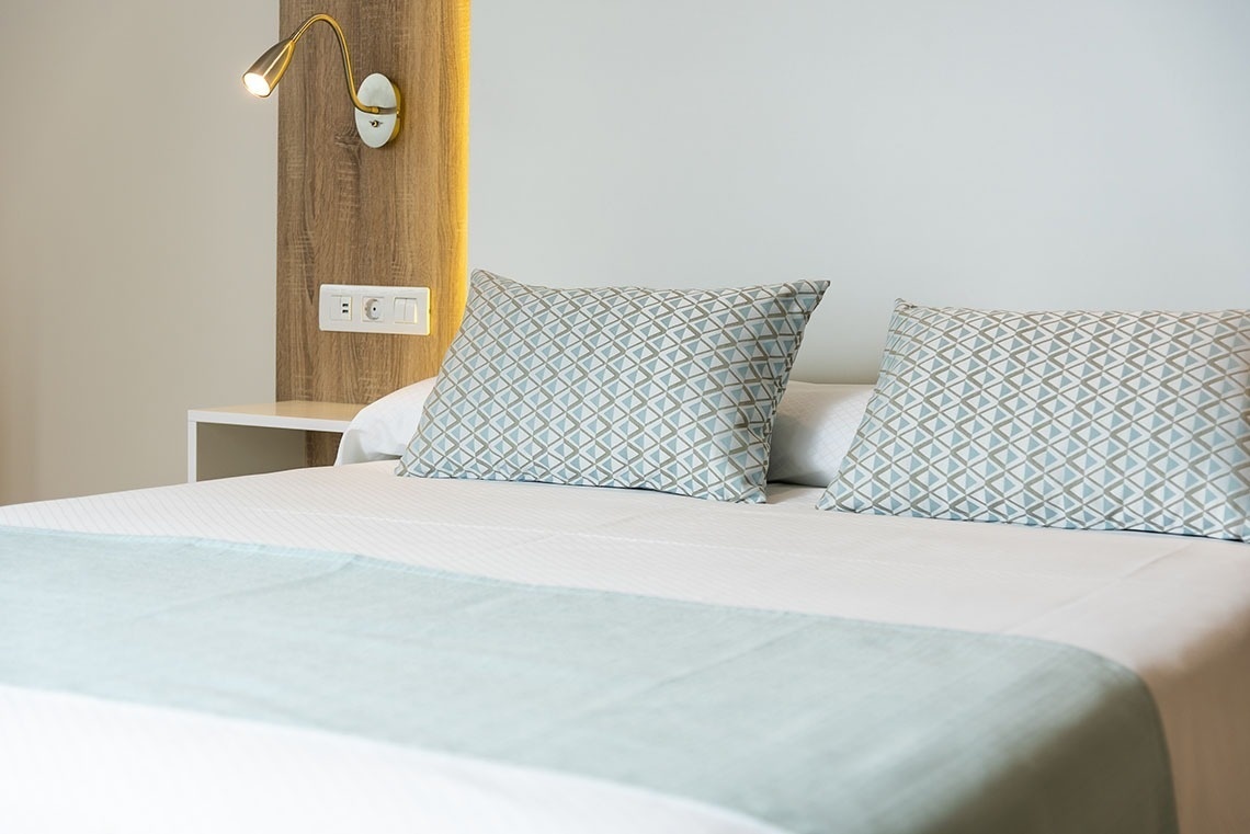 a bed with pillows and a light on the wall