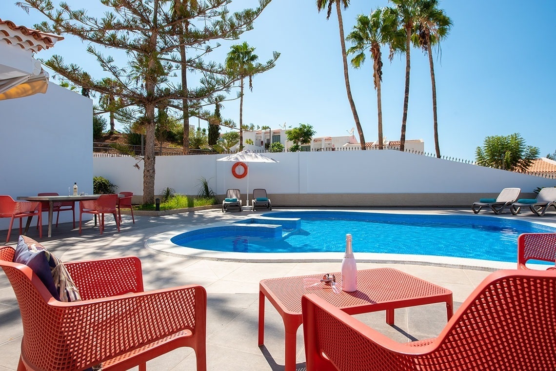 a bottle of wine sits on a table in front of a swimming pool