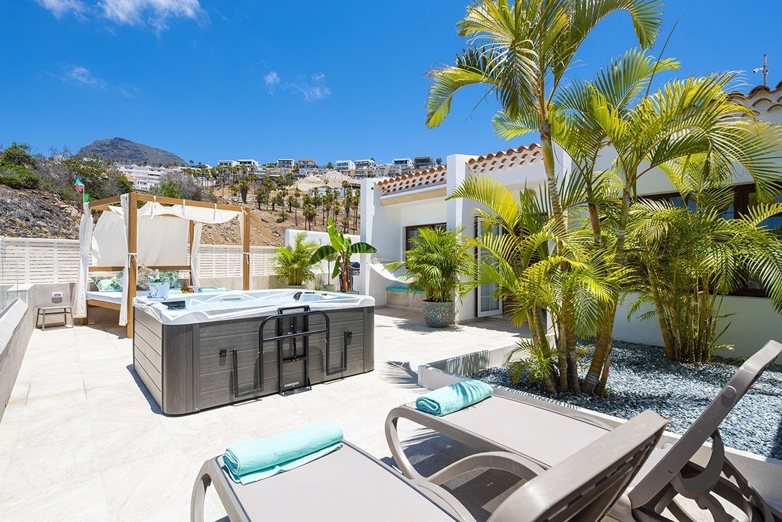 a hot tub is surrounded by palm trees and chairs