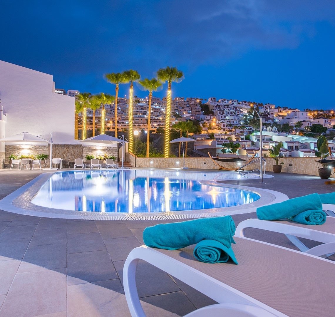 a large swimming pool is lit up at night