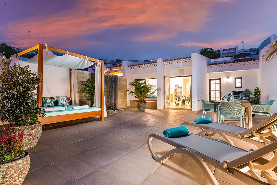 a patio with a canopy bed and lounge chairs
