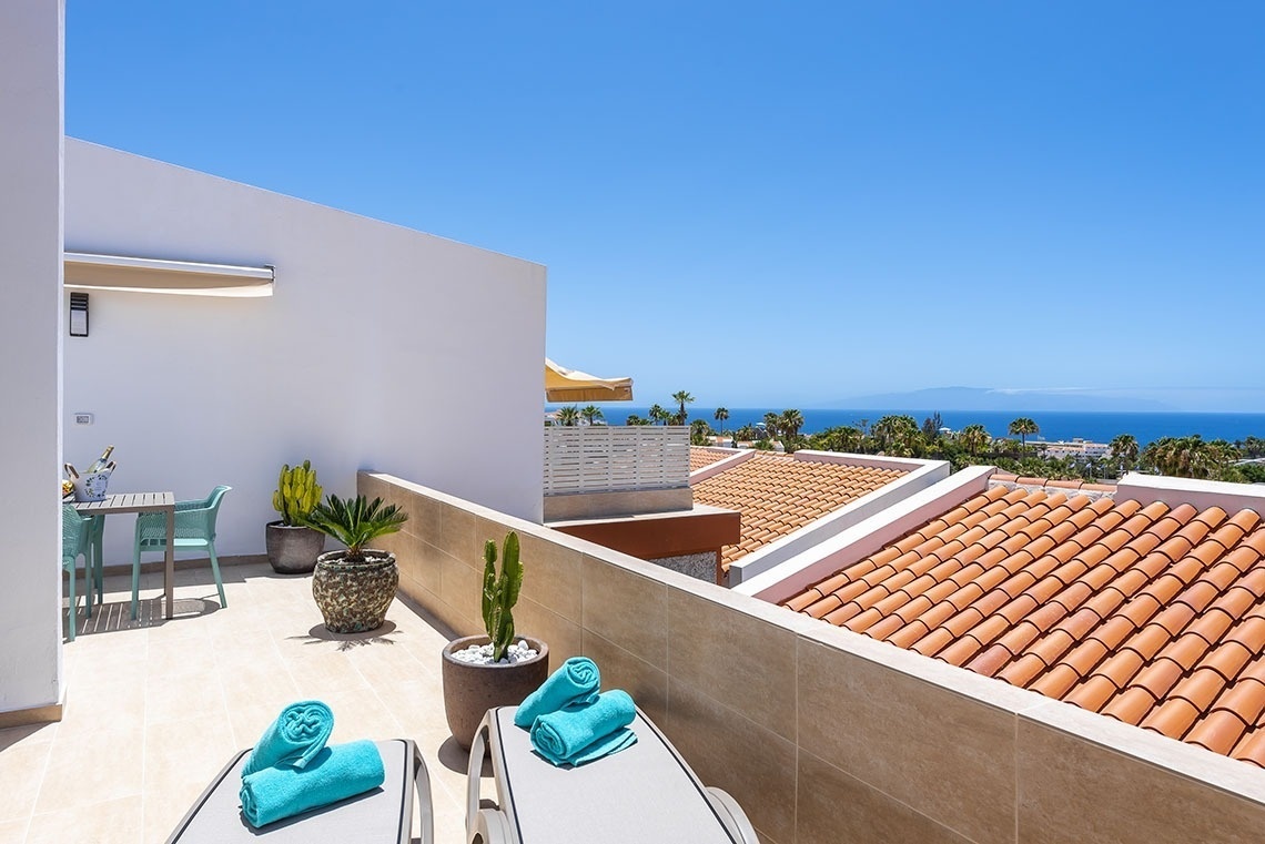 a balcony with a view of the ocean and palm trees