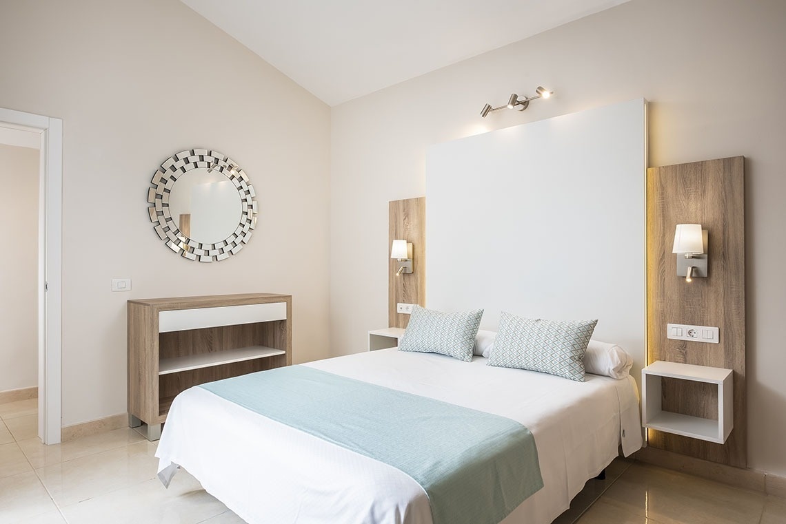 a bedroom with a bed and a mirror on the wall