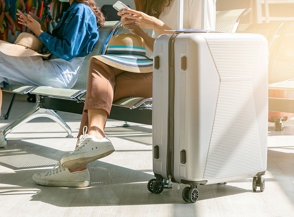 a woman sits on a chair next to a white suitcase