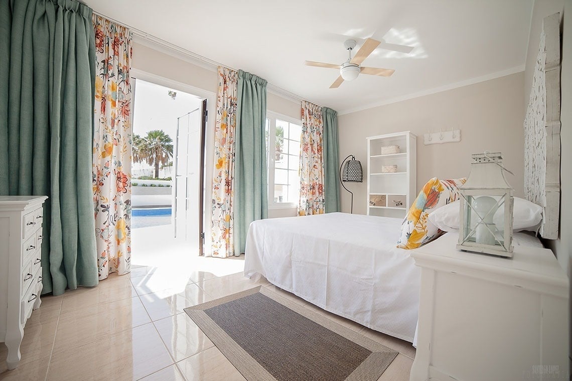 a bedroom with white curtains and a ceiling fan