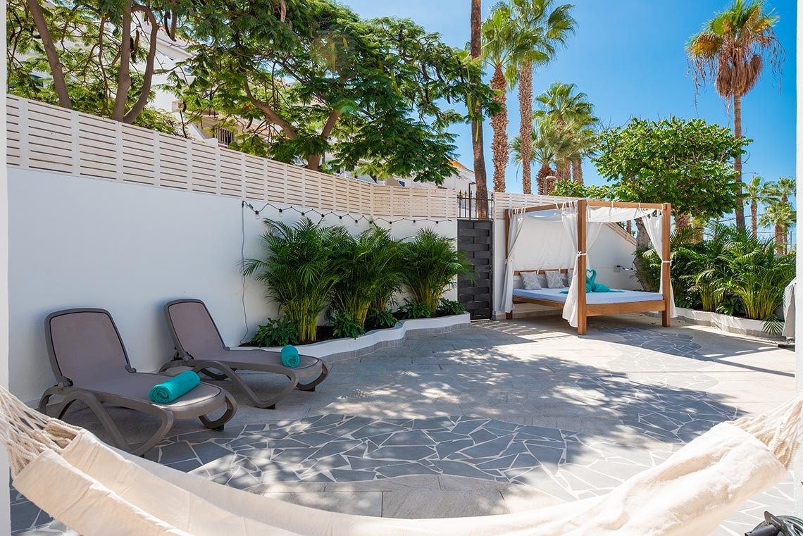 a canopy bed in a backyard with chairs and a hammock