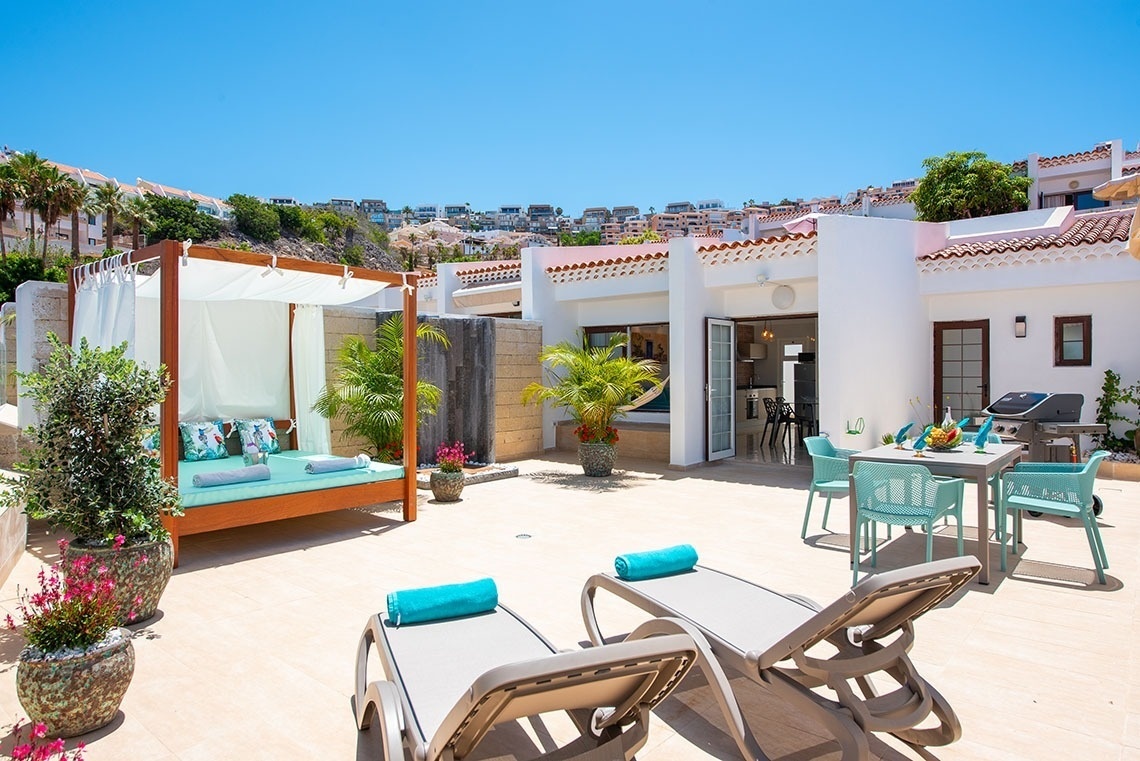 a patio with a canopy bed and a table and chairs