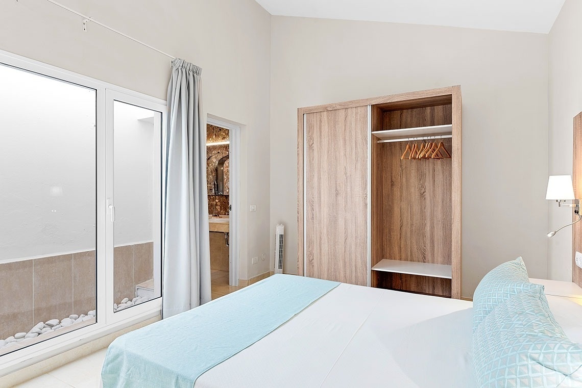 a bedroom with a bed and a closet with clothes hanging on it