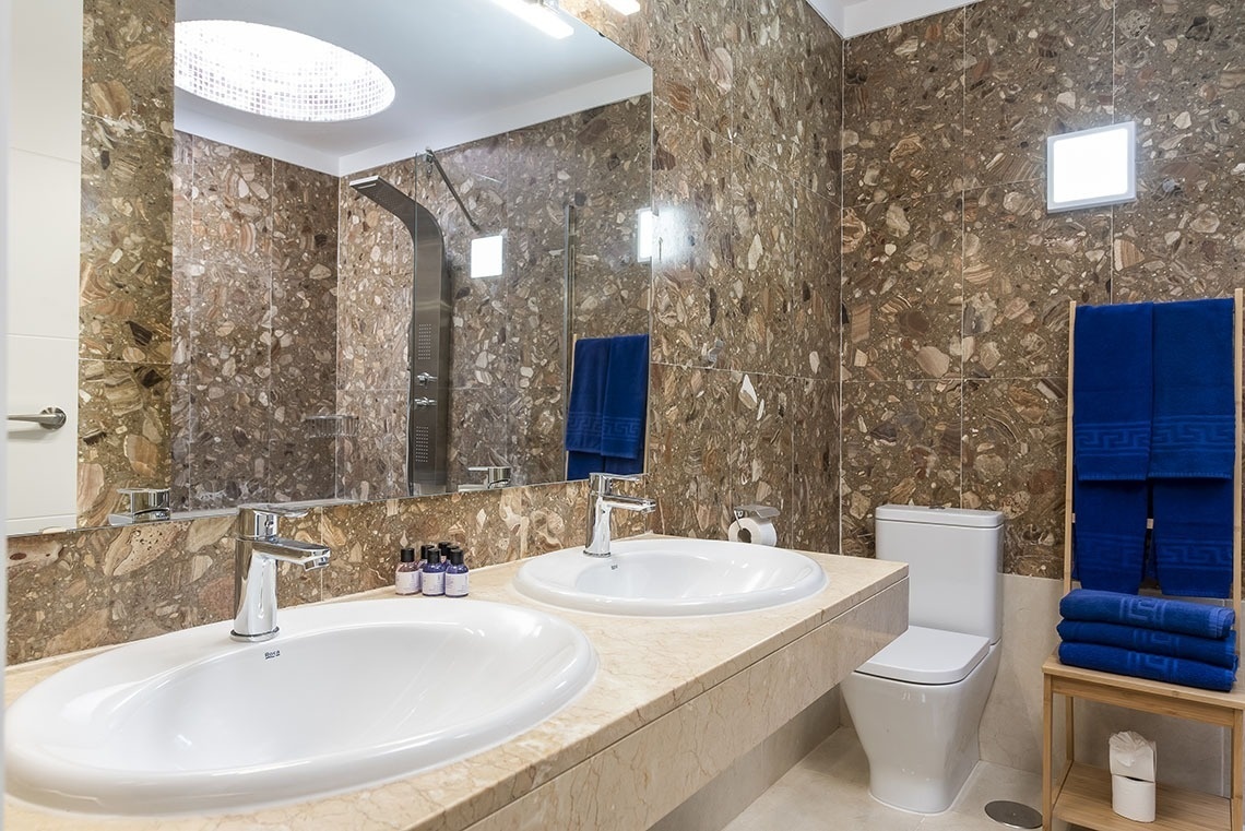 a bathroom with two sinks and a toilet with blue towels that say versace