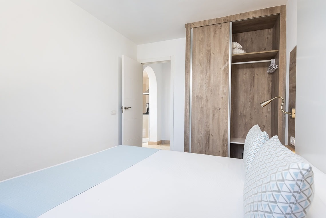 a bedroom with a bed and a closet with clothes on the shelves