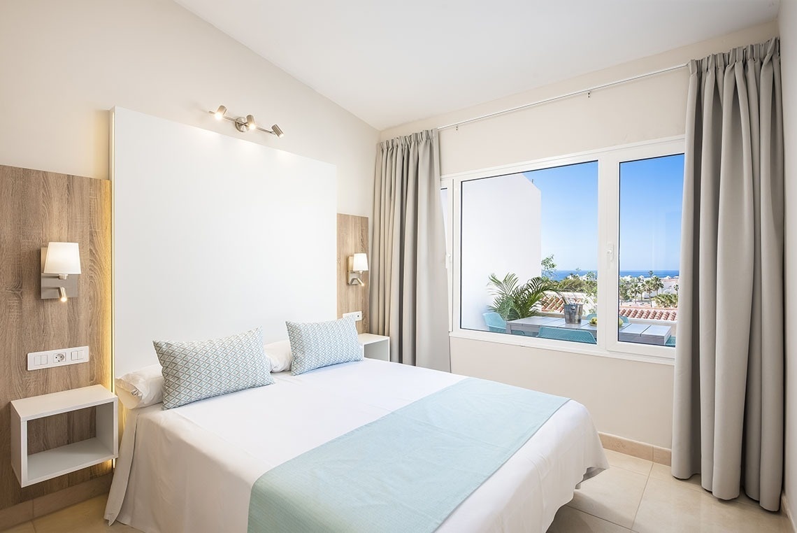 a bedroom with a bed and a window with a view of the ocean