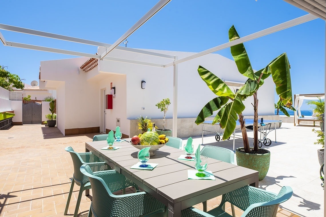 a table with green chairs and a bowl of fruit on it