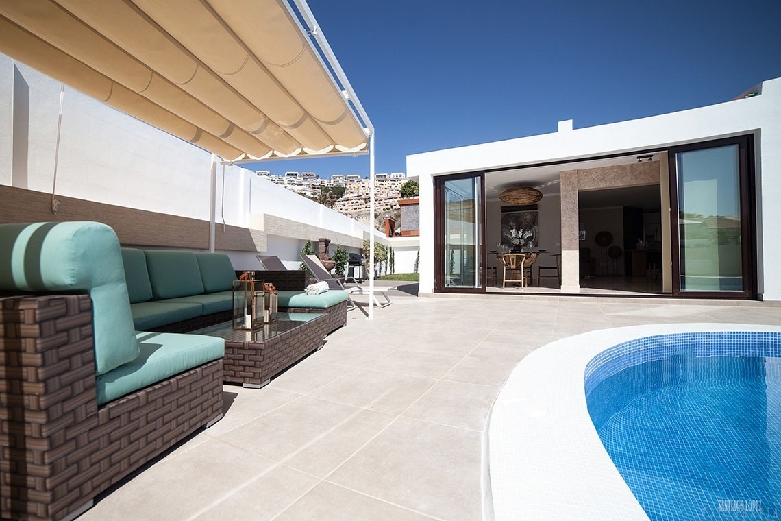 a patio with a couch and a table next to a pool