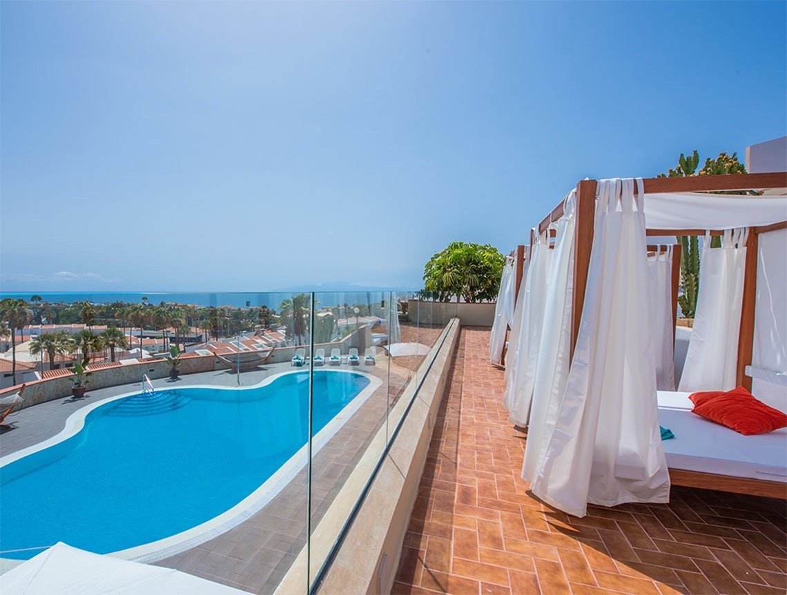 una cama con dosel y una piscina en el fondo