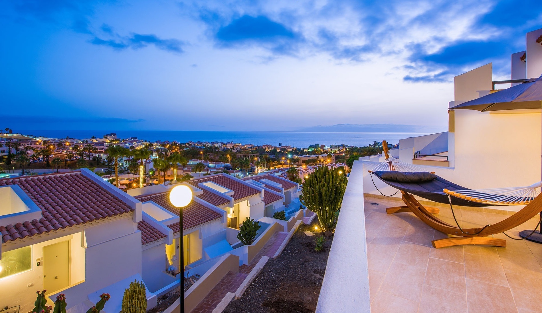 a hammock sits on a balcony overlooking a city and the ocean