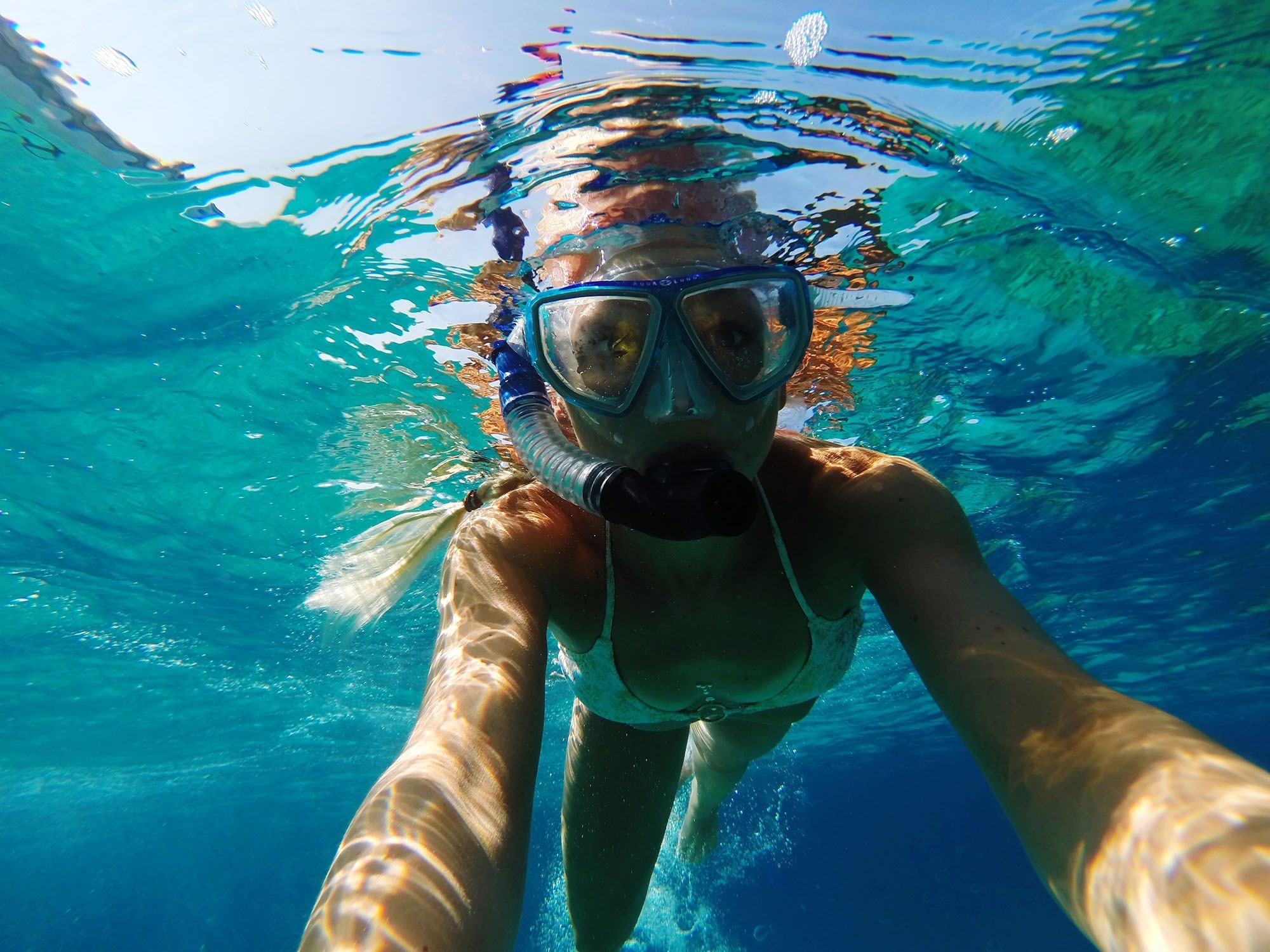 una mujer bucea en el océano con una máscara y gafas