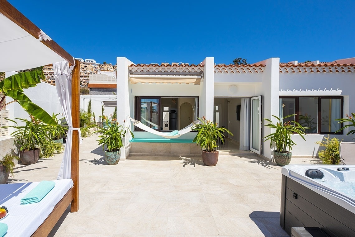 a patio with a hammock and a hot tub