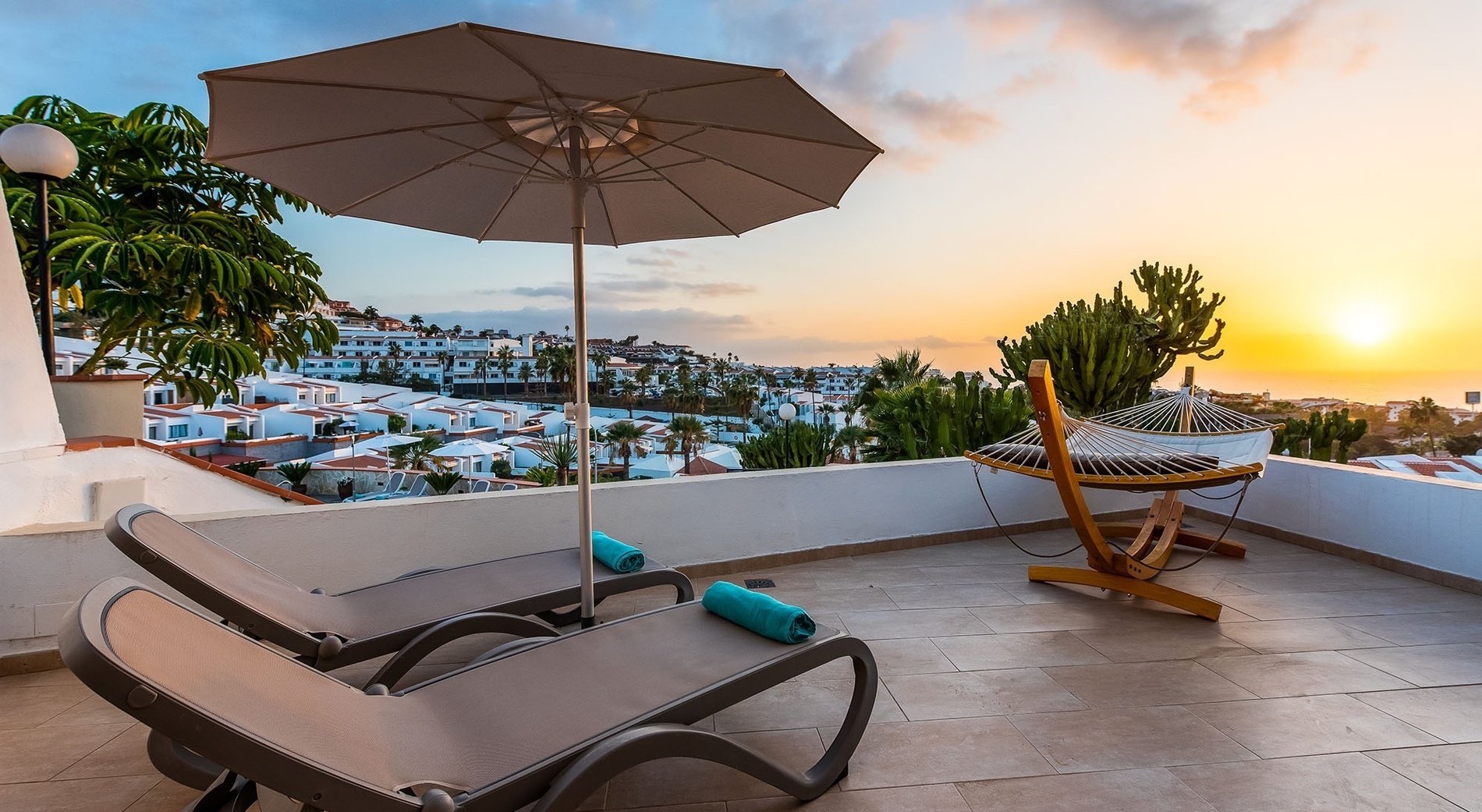 un balcón con sillas y hamaca al atardecer