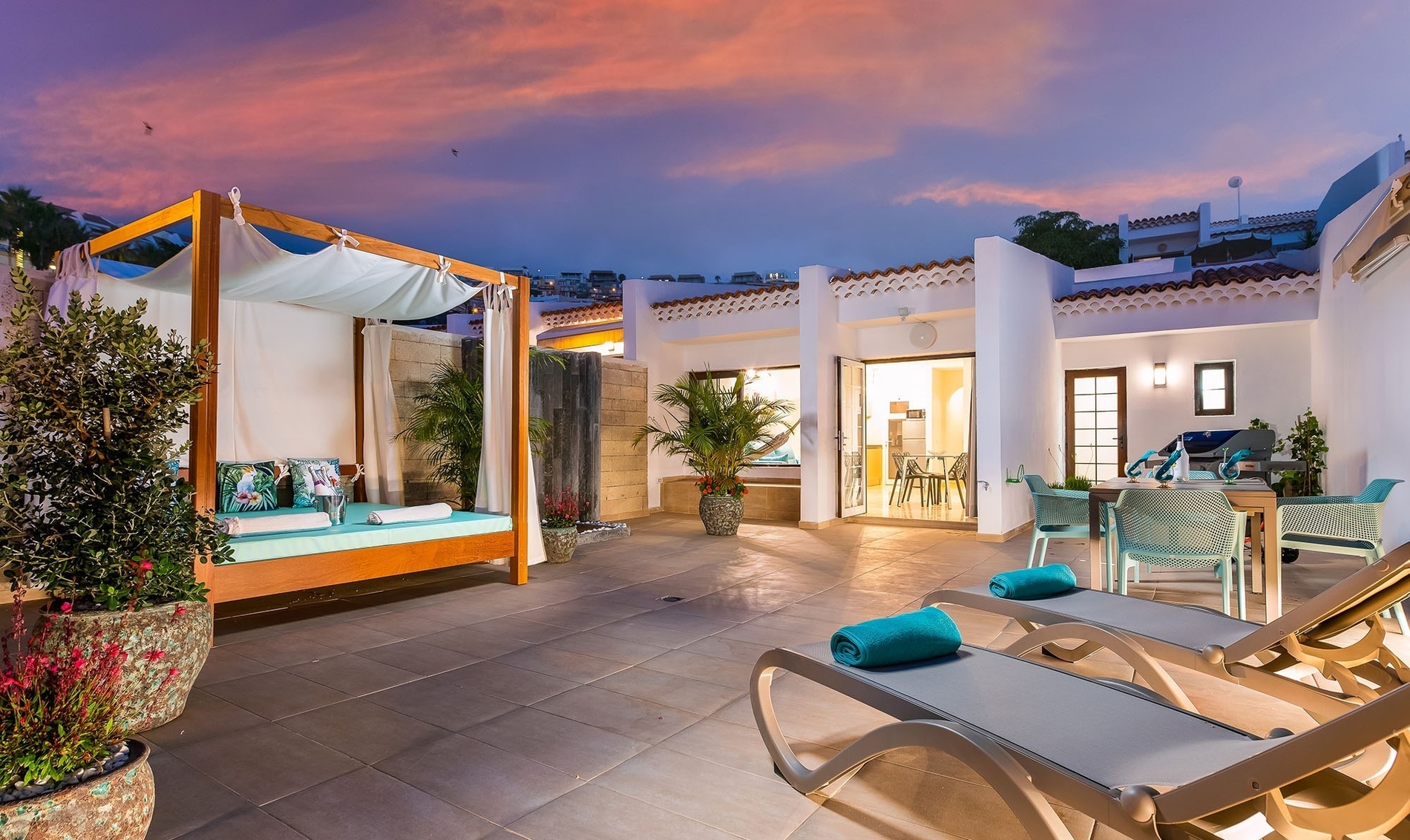 a patio with a canopy bed and lounge chairs