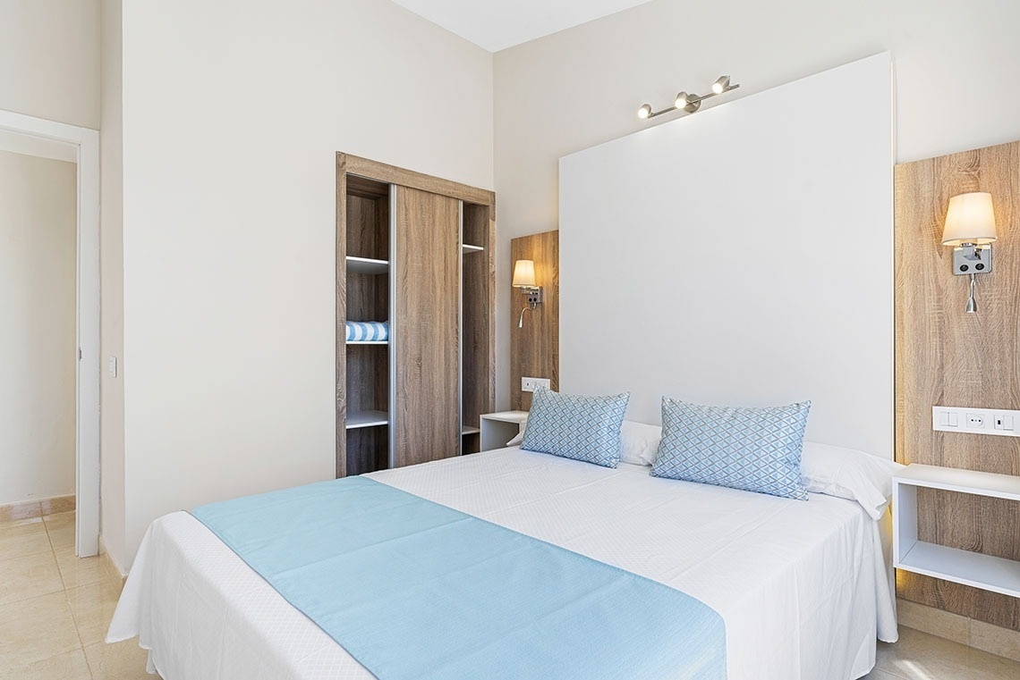 a bed with a blue blanket and pillows in a hotel room