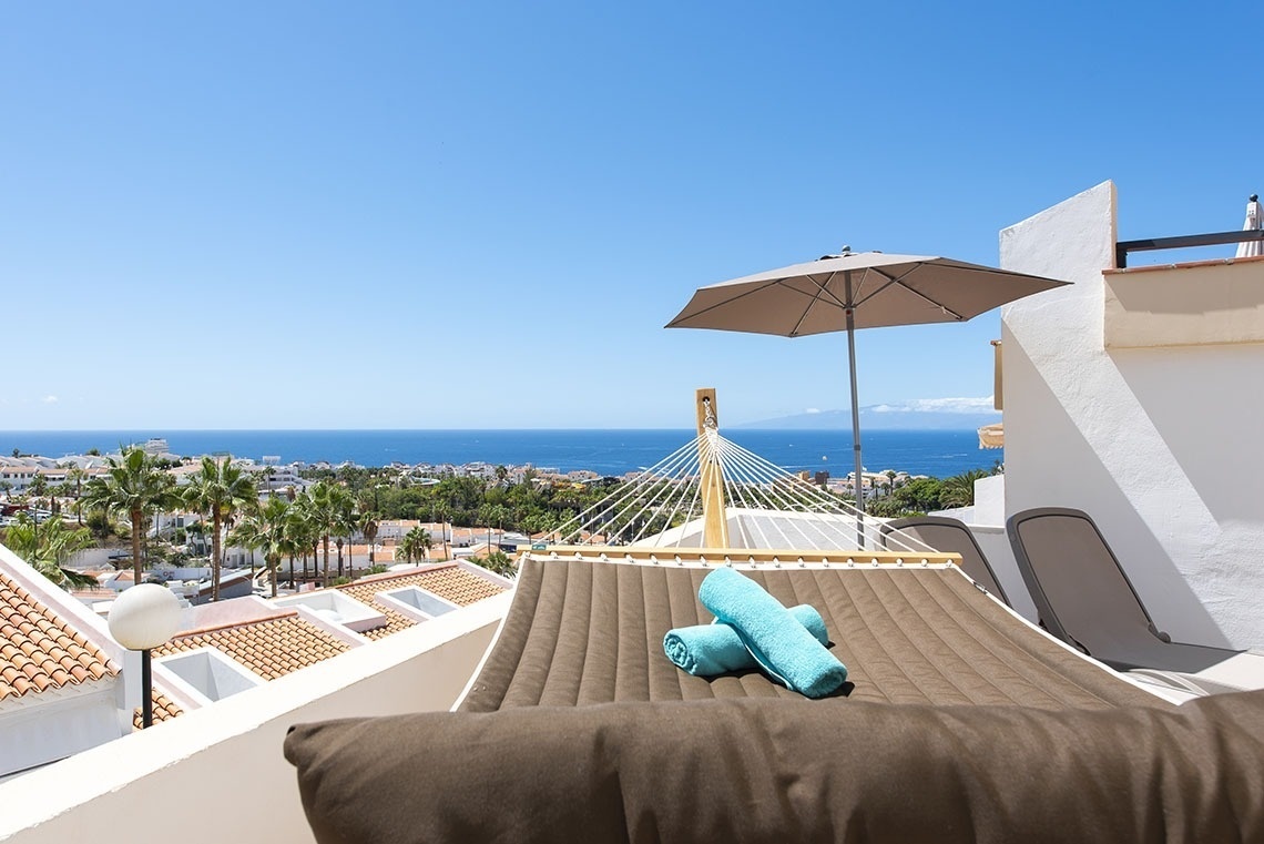 a hammock with towels on it and an umbrella overlooking the ocean