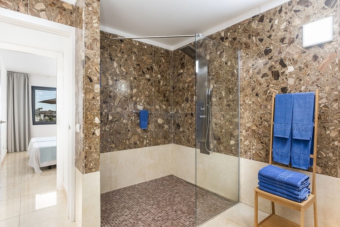 a bathroom with a walk in shower and greek key towels