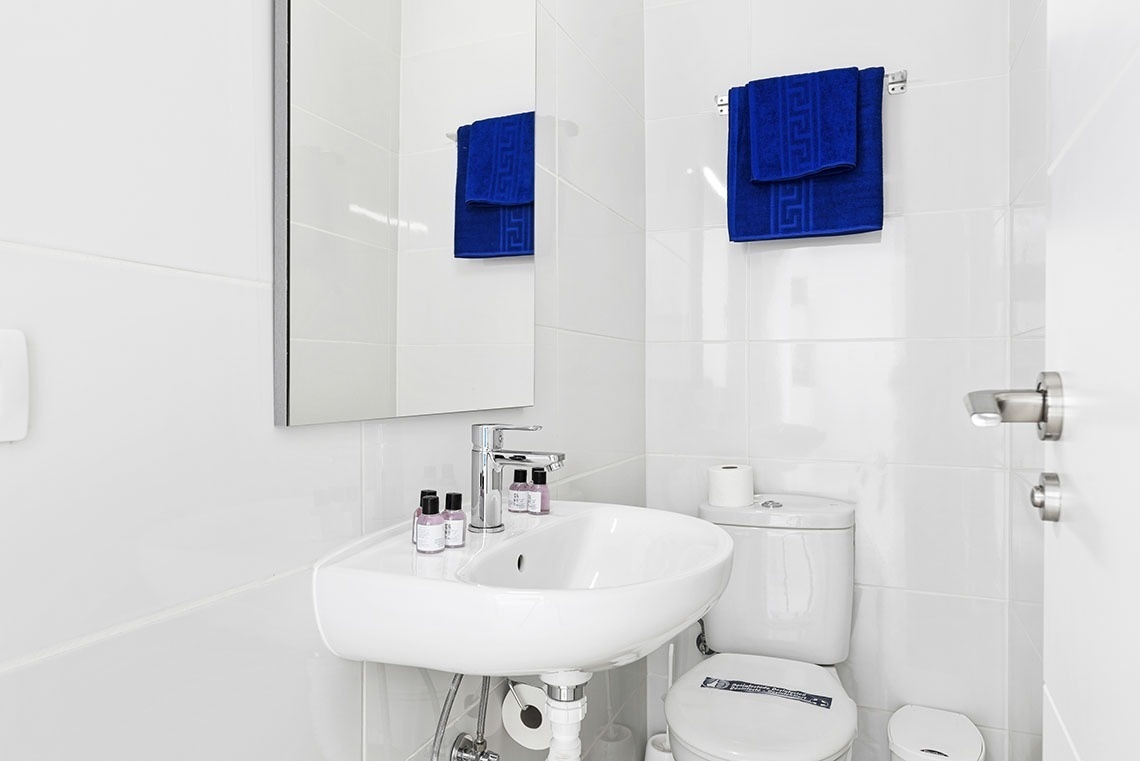 a bathroom with a sink toilet and mirror with blue towels on the wall