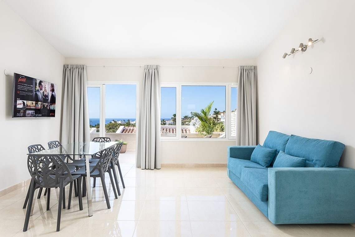 a living room with a blue couch and a flat screen tv that says netflix