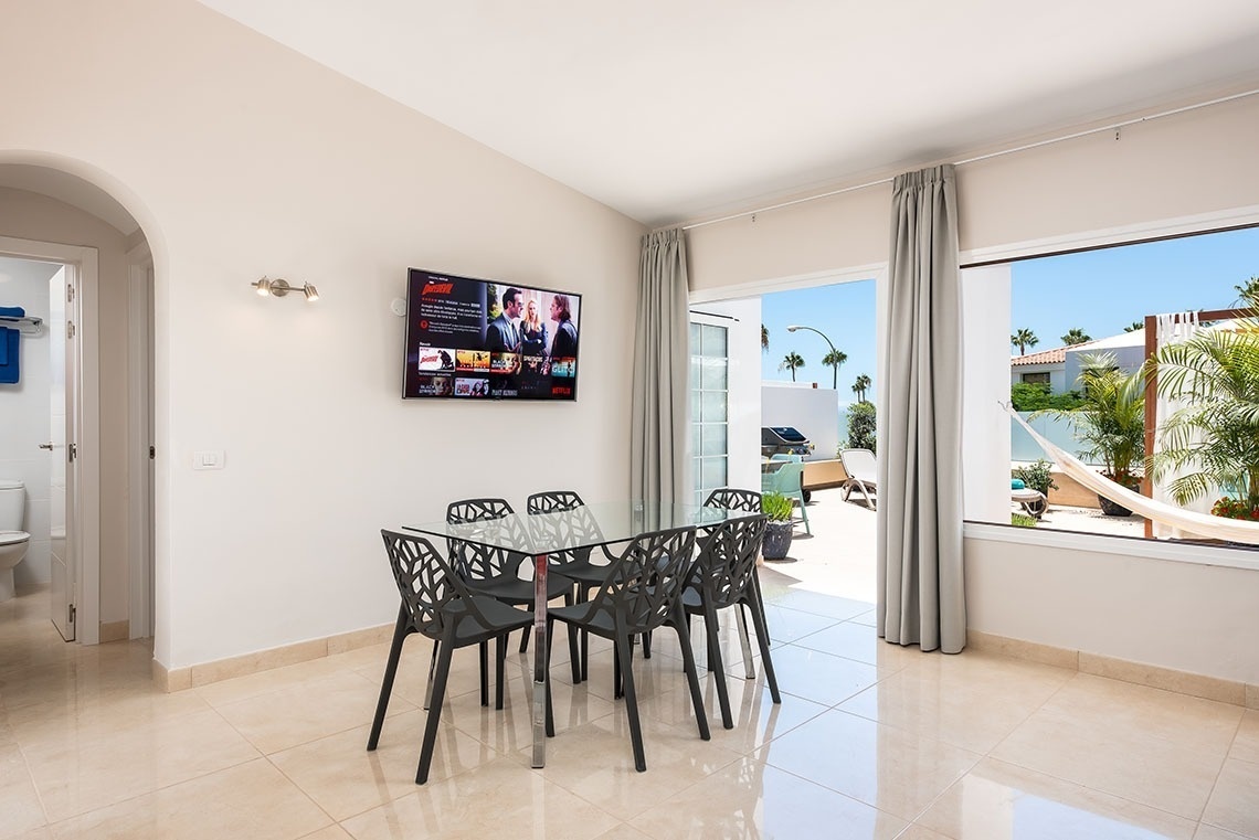 a dining room with a table and chairs and a flat screen tv that says netflix on it