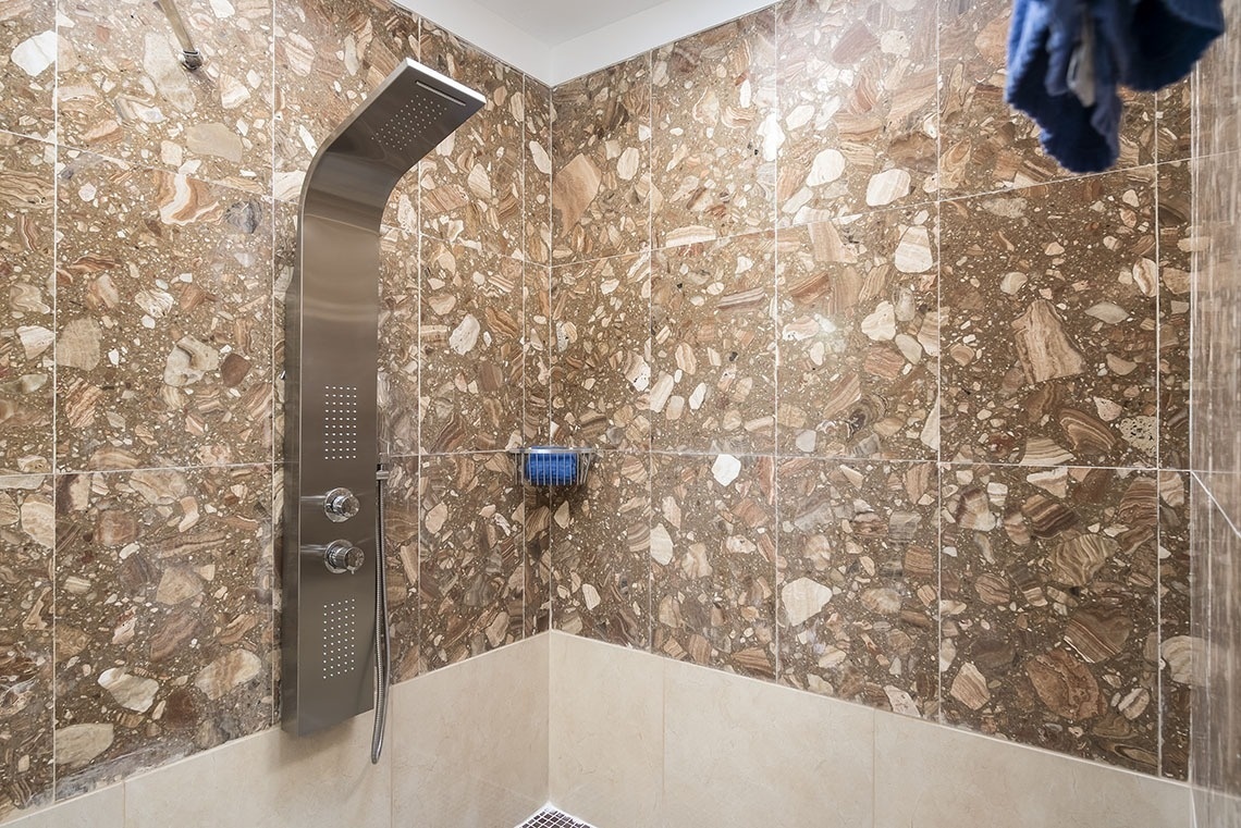 a shower head in a bathroom with a marble wall