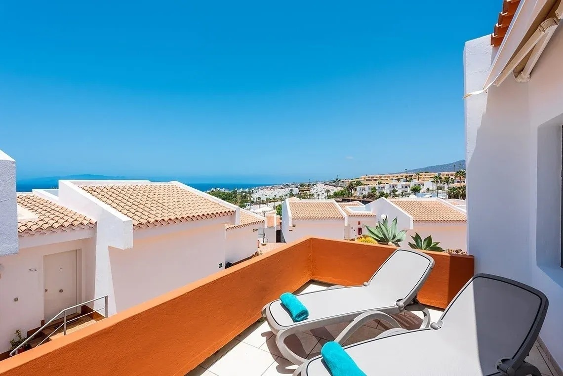 un balcón con dos tumbonas y una vista al océano