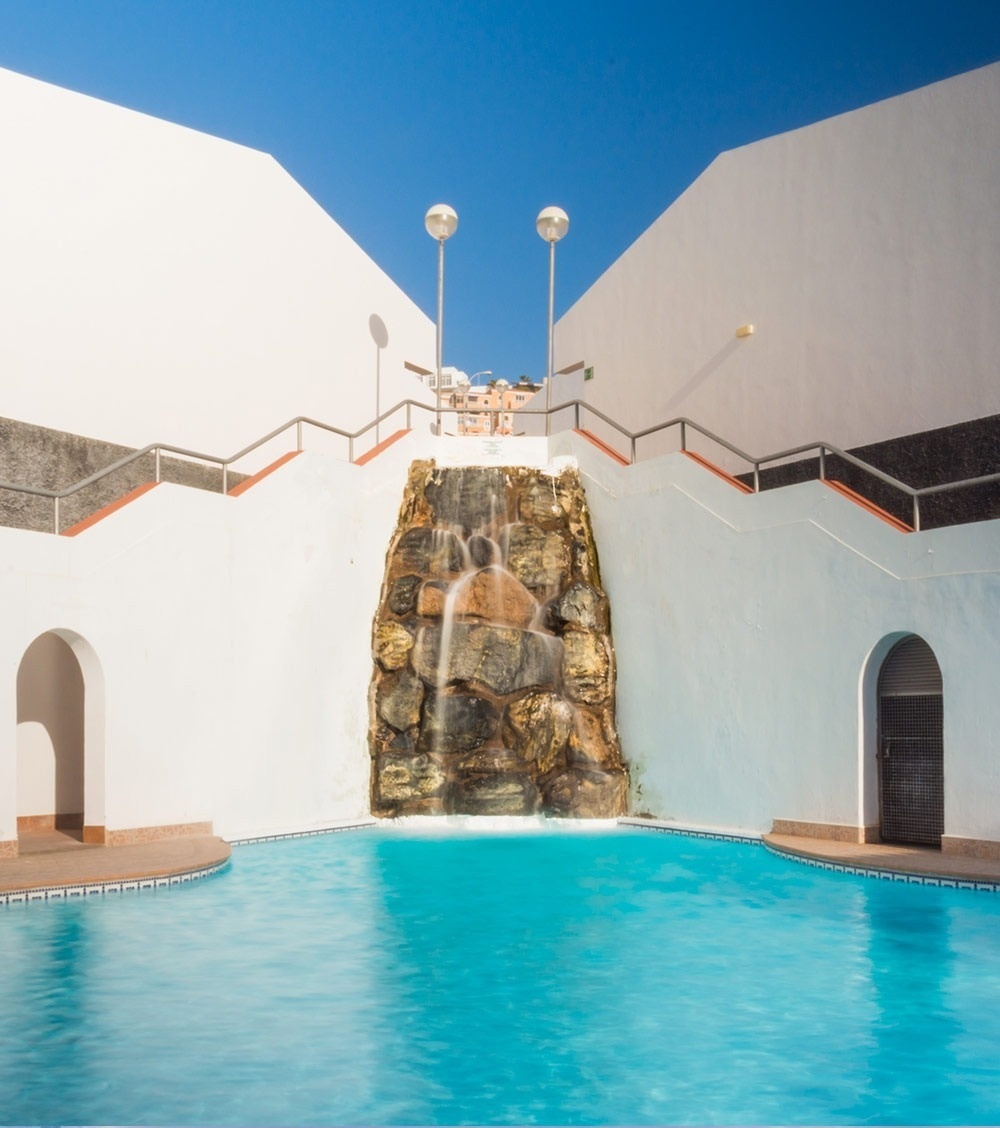 una hamaca se sienta junto a una piscina al atardecer