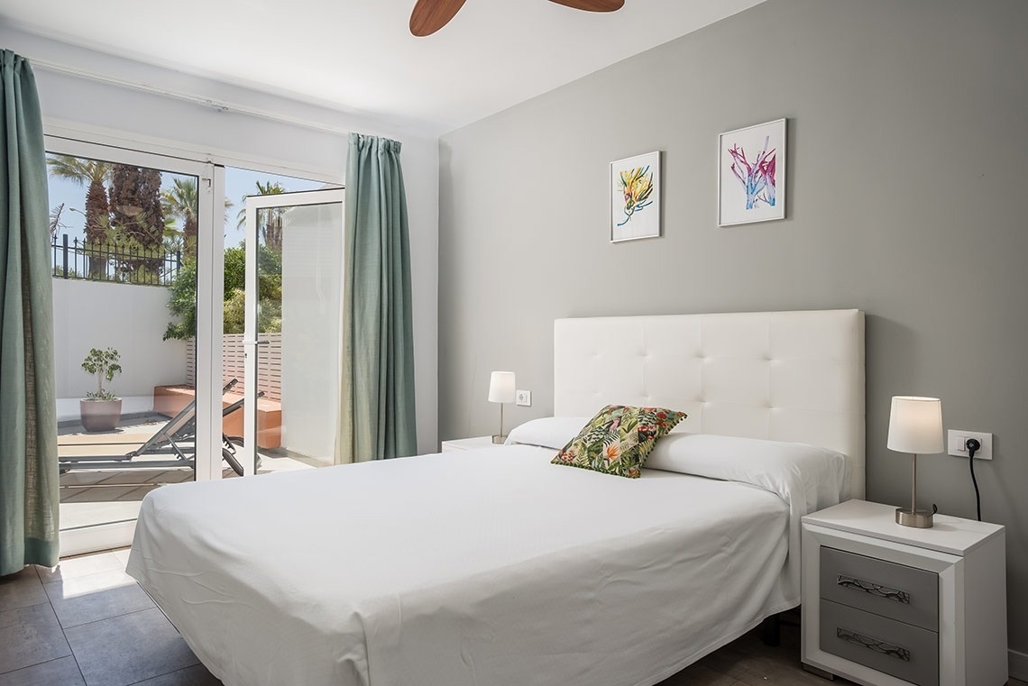 un dormitorio con una cama blanca y un ventilador de techo