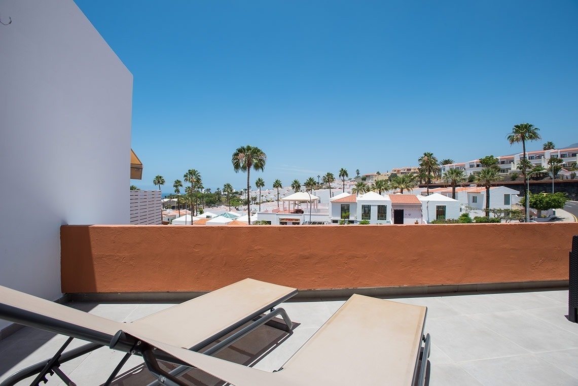 dos tumbonas en un balcón con palmeras en el fondo