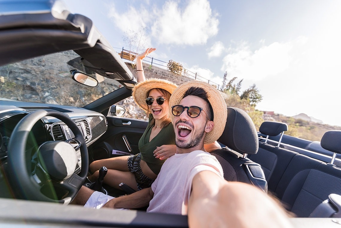un hombre y una mujer se toman una selfie en un auto convertible