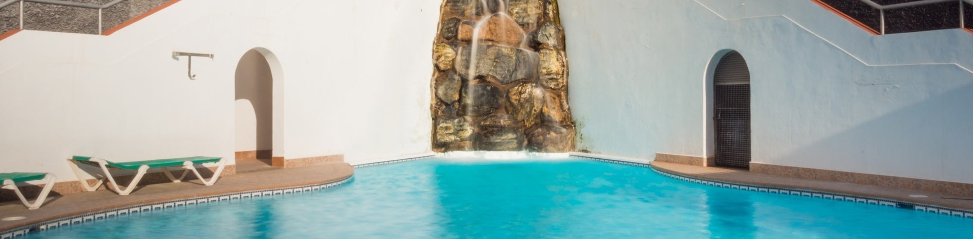 Liegestühle und Sonnenschirme umgeben einen großen Swimmingpool