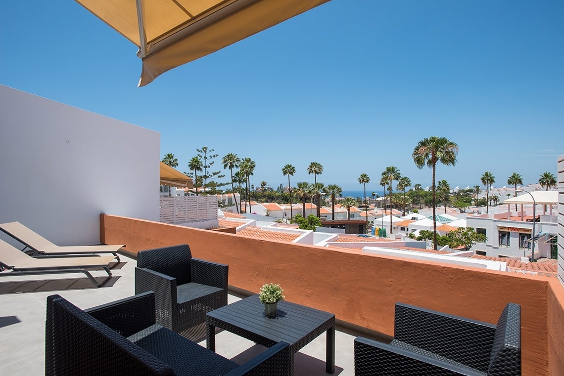 una hamaca y un paraguas en un balcón con vista al océano