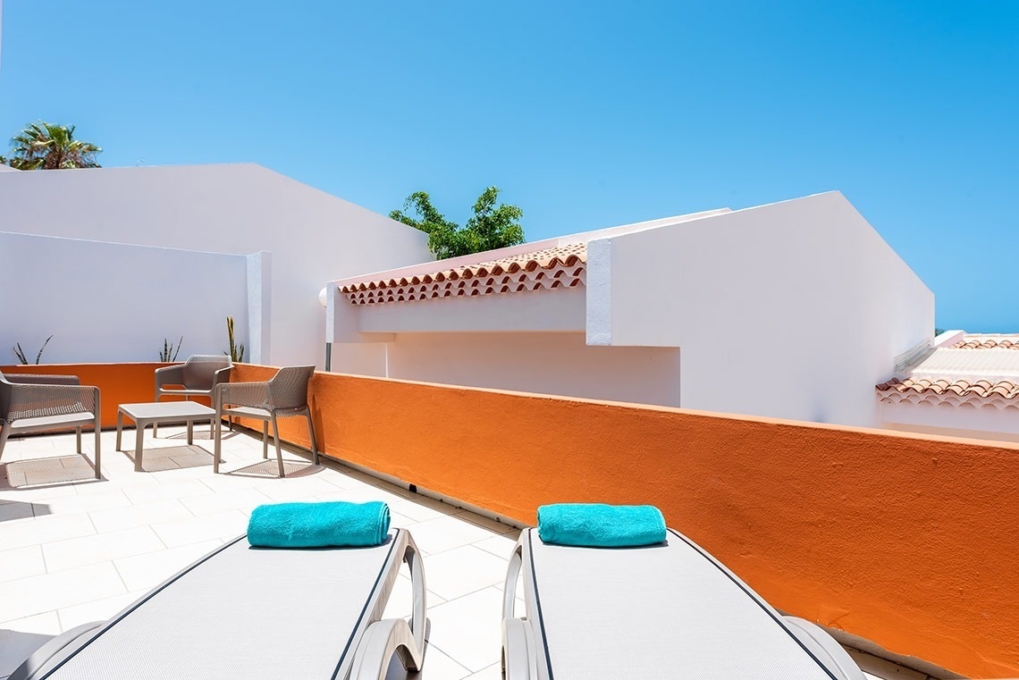 dos tumbonas blancas con toallas azules sobre ellas