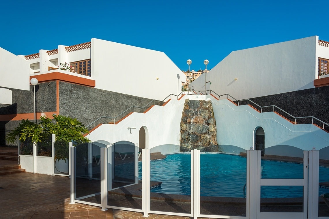 una grande piscina circondata da sedie e ombrelloni al tramonto