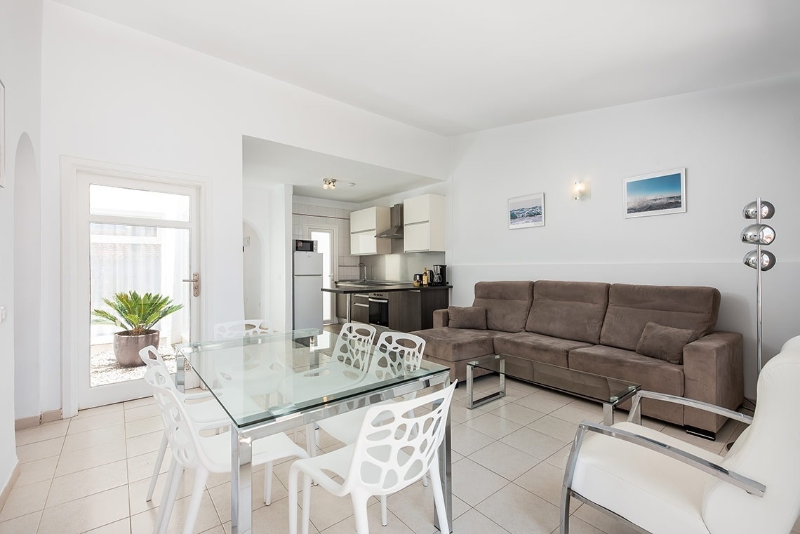 una sala de estar con un sofá marrón y una mesa y sillas blancas