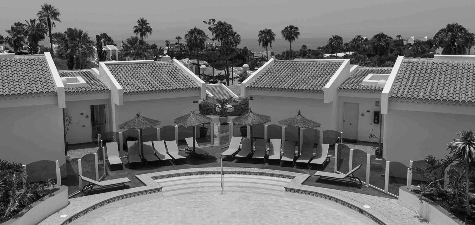 a black and white photo of a swimming pool with chairs and umbrellas=s1900