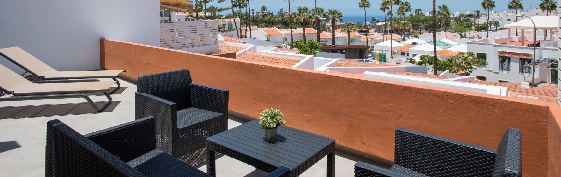 un balcón con sillas y hamaca al atardecer