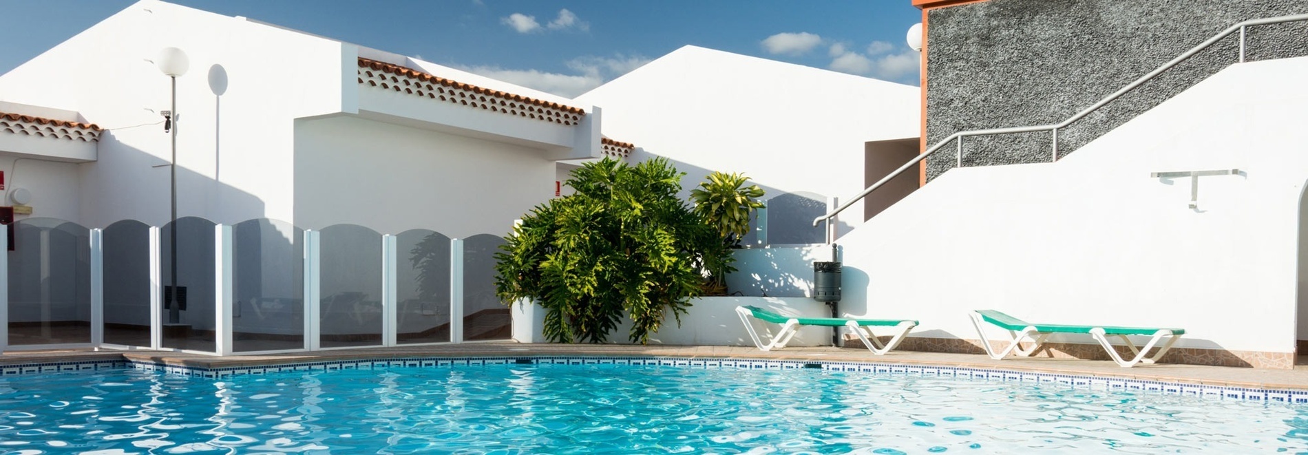 a swimming pool surrounded by chairs and potted plants