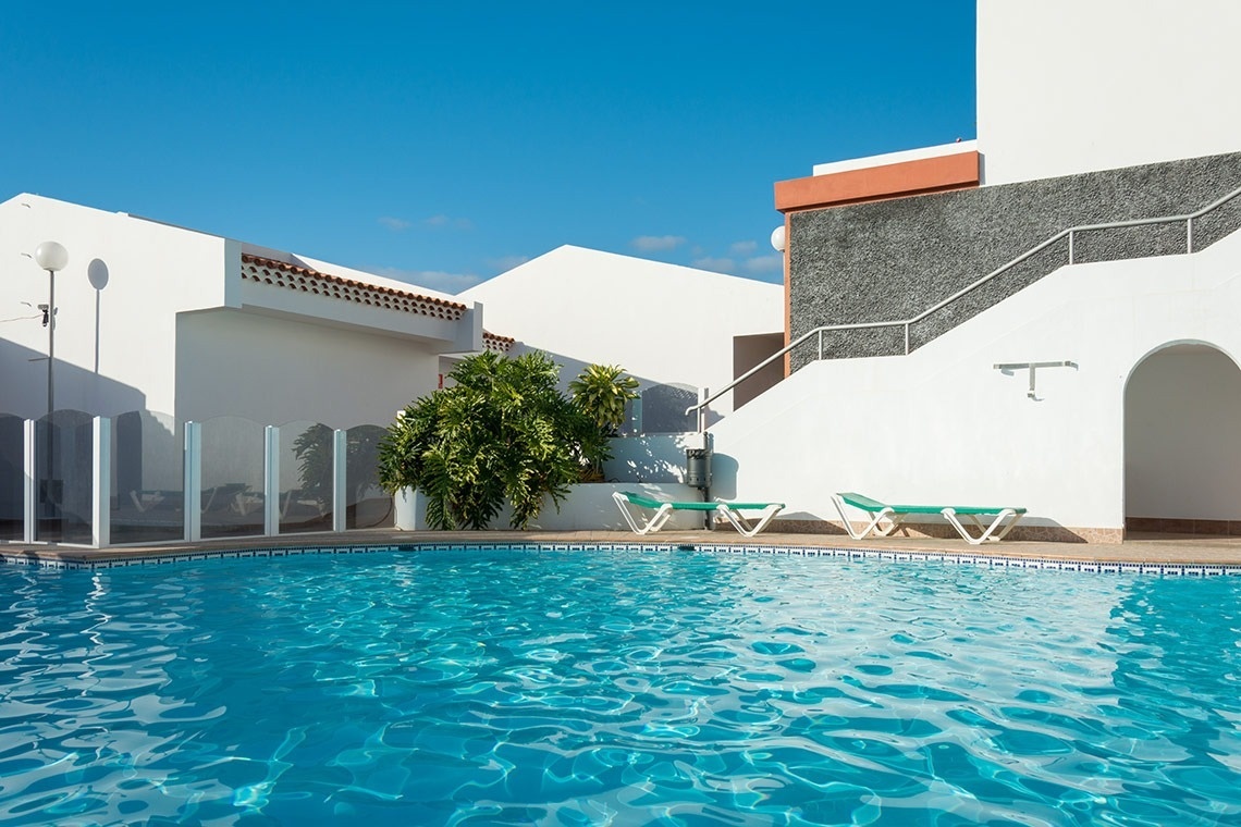 una cama con dosel y una piscina en el fondo