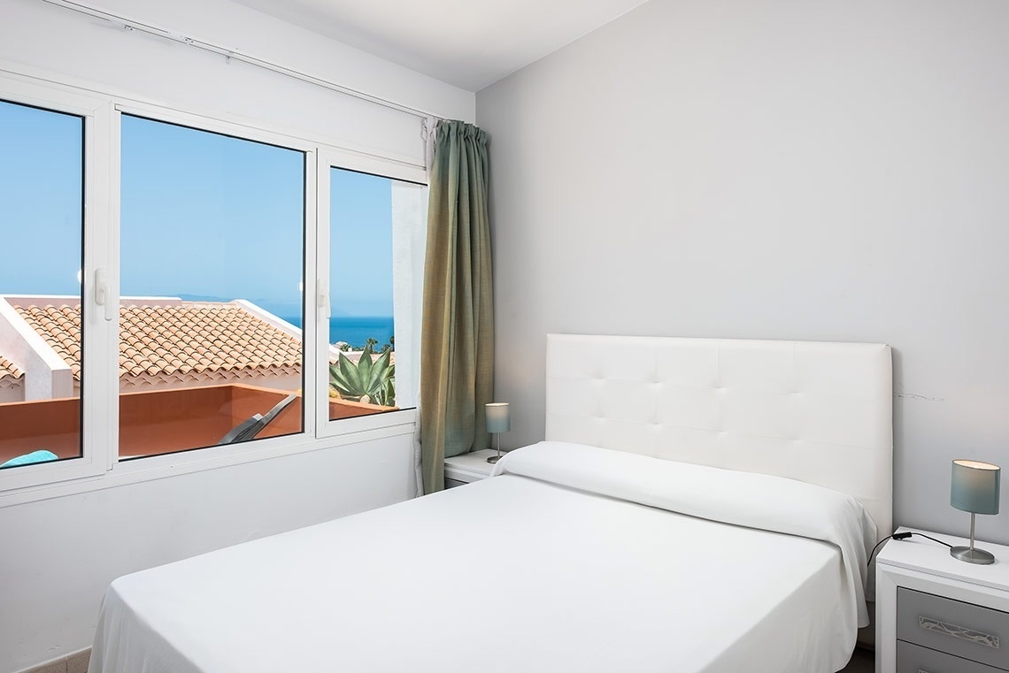 un dormitorio con una cama y una ventana con vista al océano